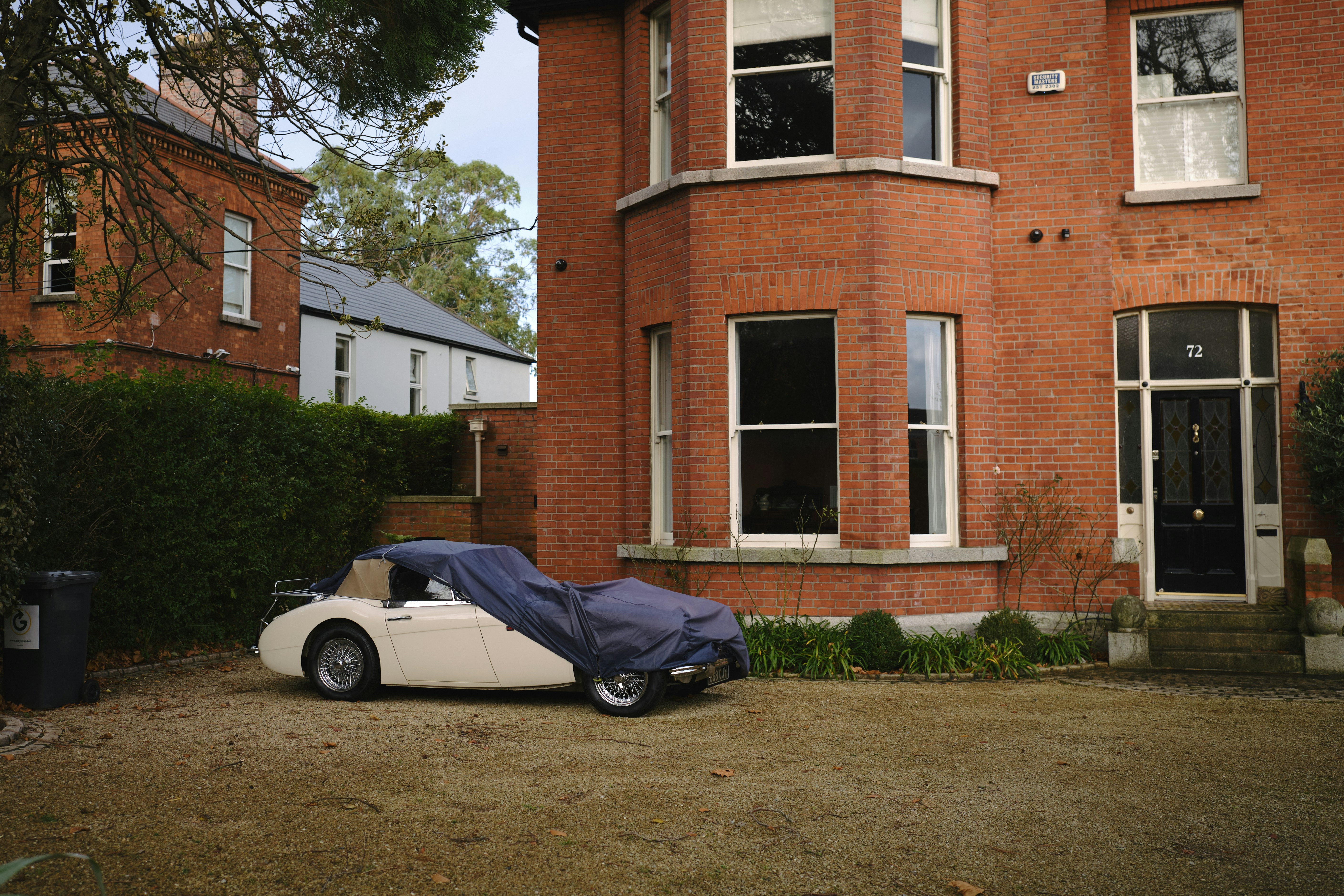 a car covered with a tarp parked in front of a house, Facade of Irish home in Sandymount village, Dublin, Ireland