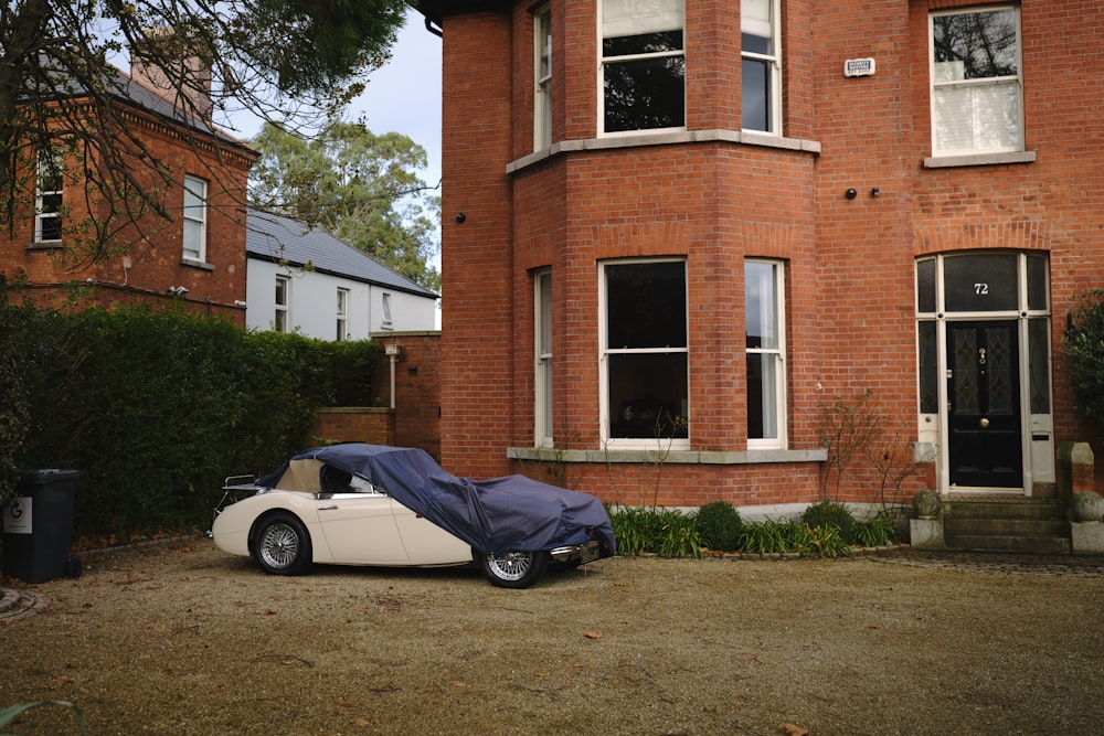 a car covered with a tarp parked in front of a house