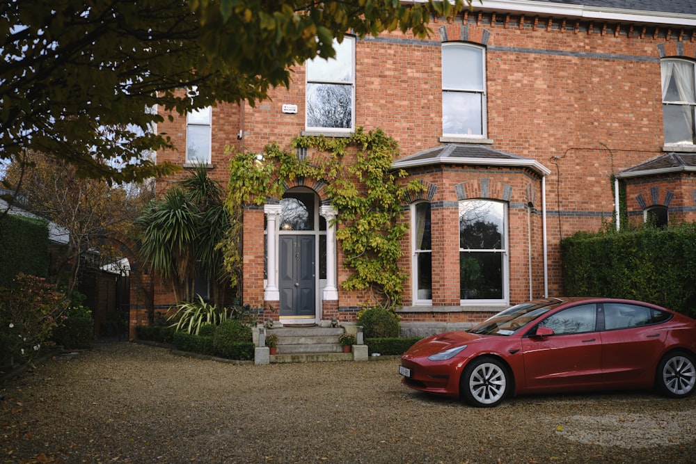 a red car parked in front of a brick house