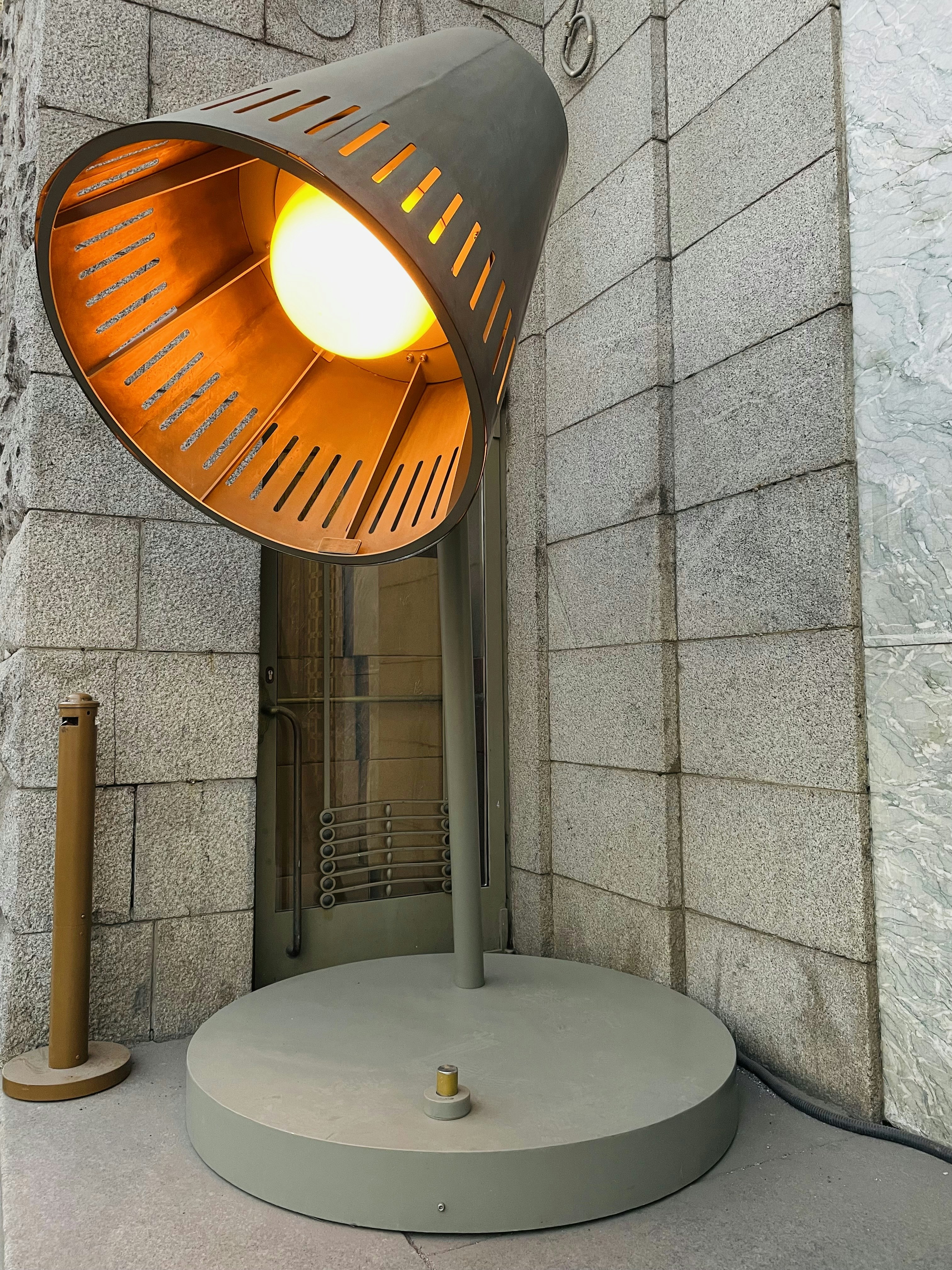 a lamp sitting on top of a cement floor next to a wall