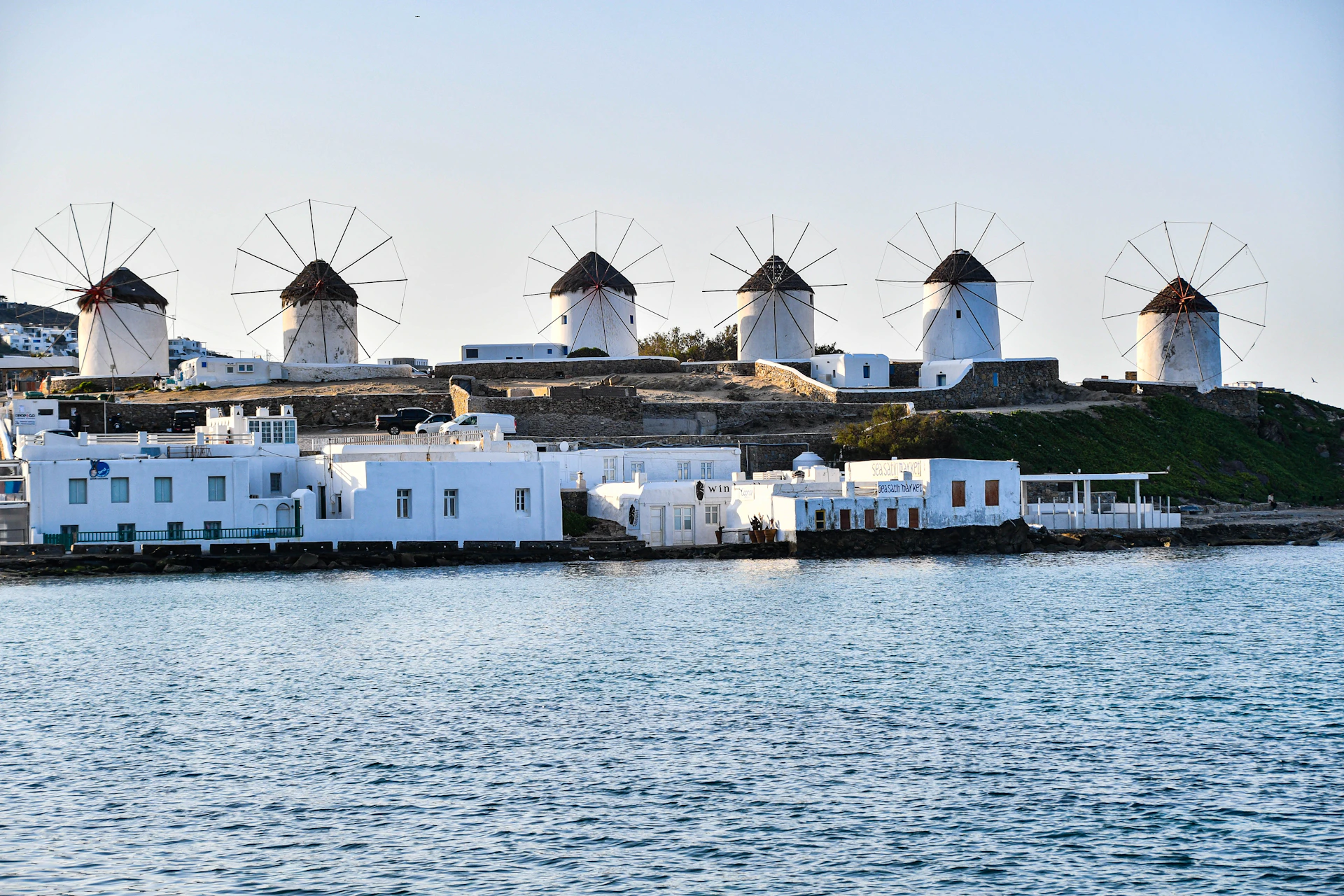 a row of windmills sitting on top of a hill next to a body of