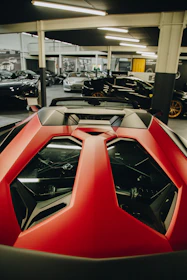 A vibrant red sedan parked in a futuristic showroom with interactive photo displays.