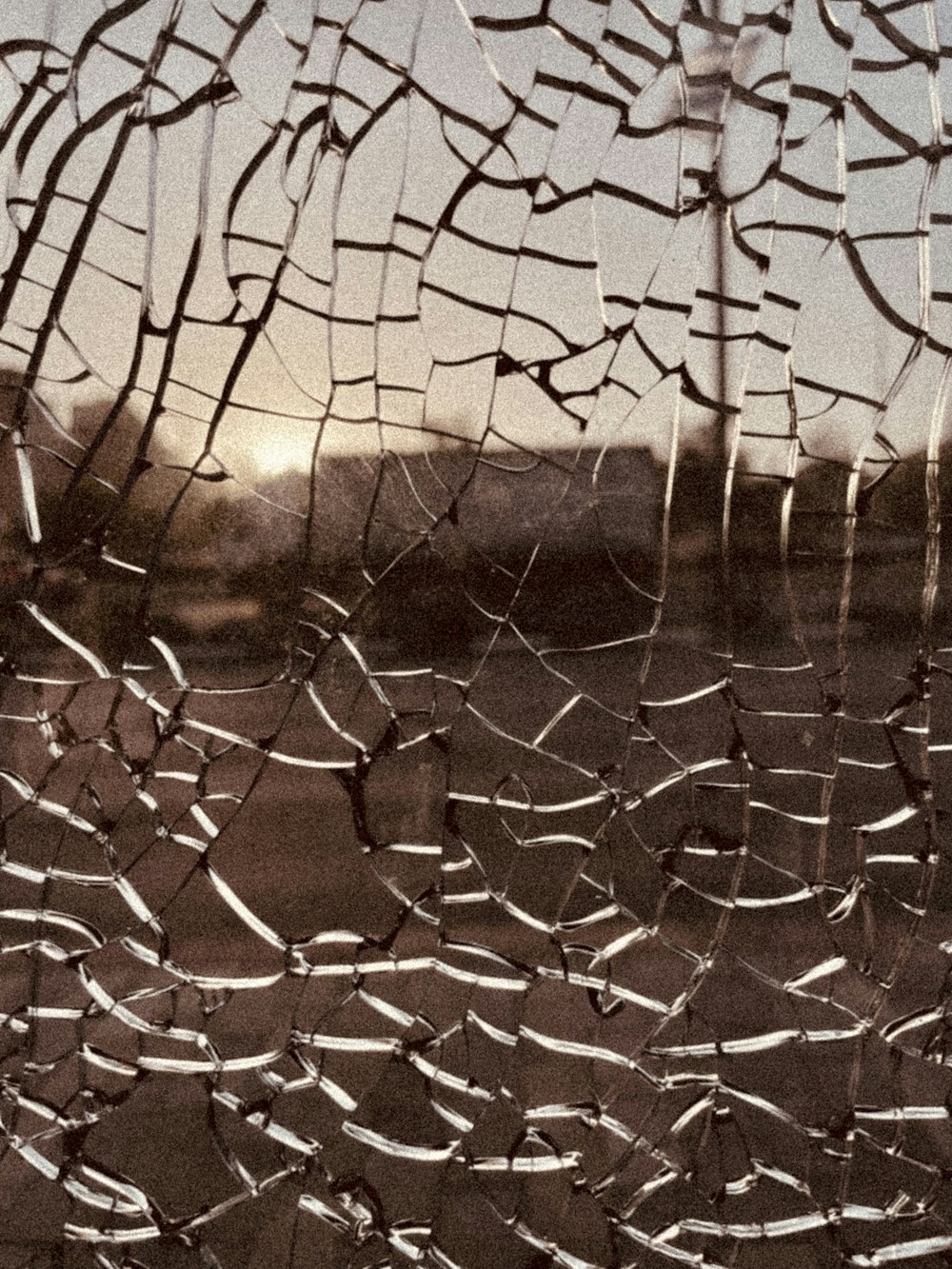 a broken glass window with a view of a field