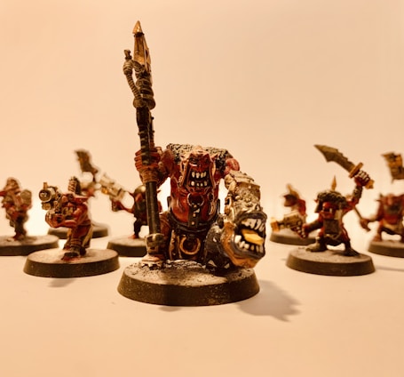 Close-up photo of detailed resin action figures and miniatures arranged artistically on a wooden table.