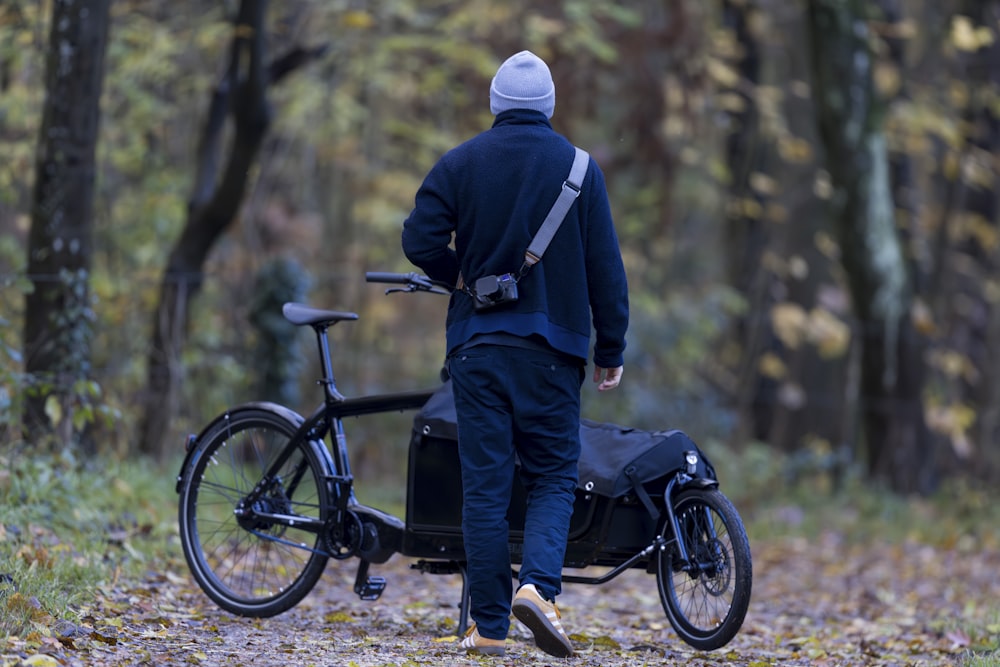 a man walking with a bike in the woods