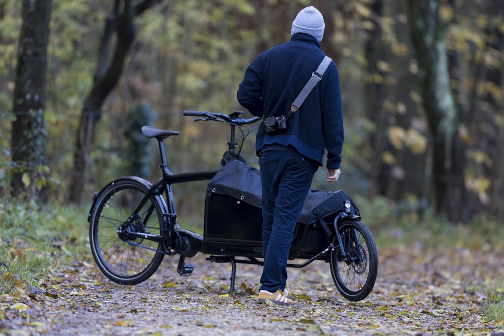 a man walking with a bike in the woods