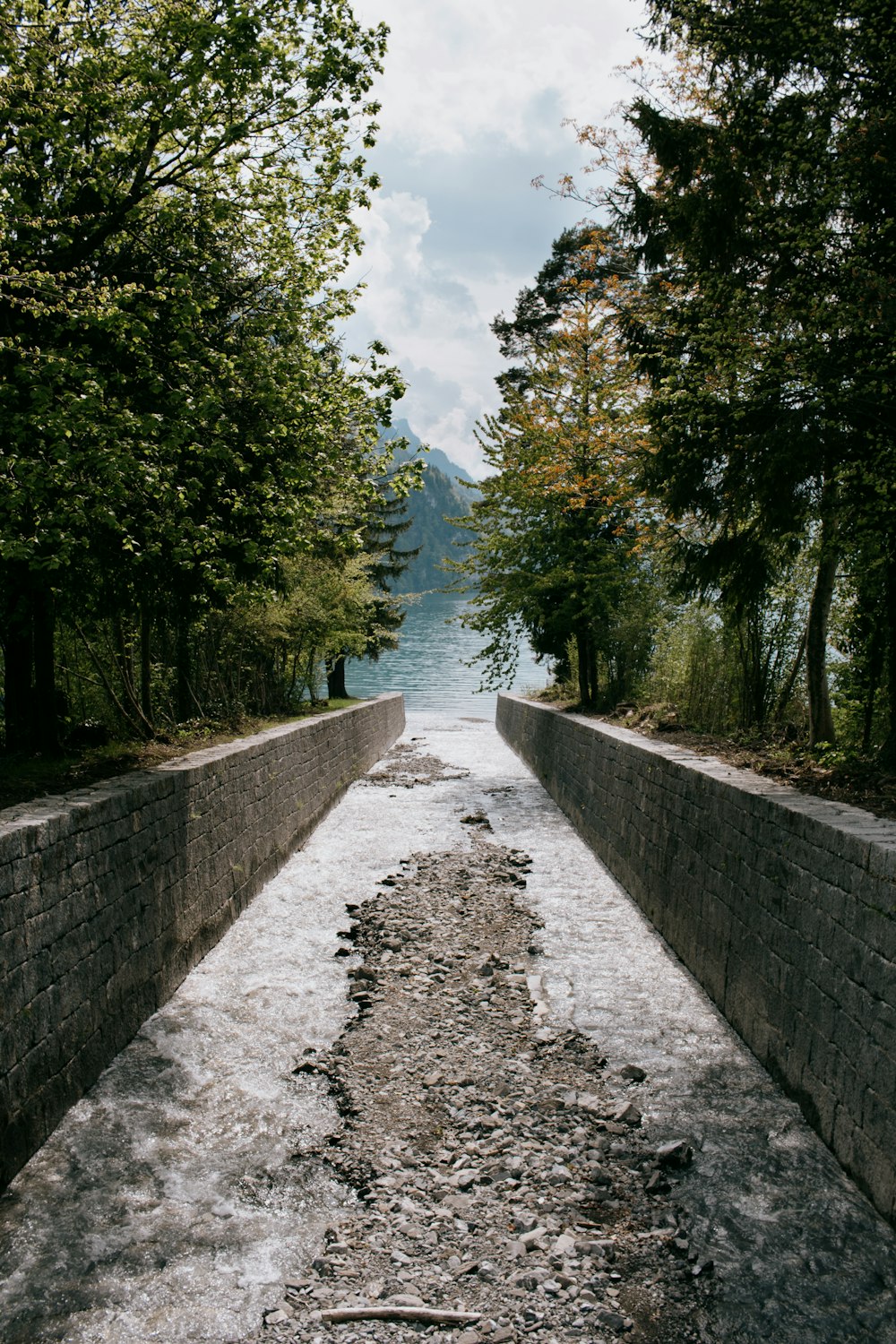 a stone wall with a path leading to a body of water