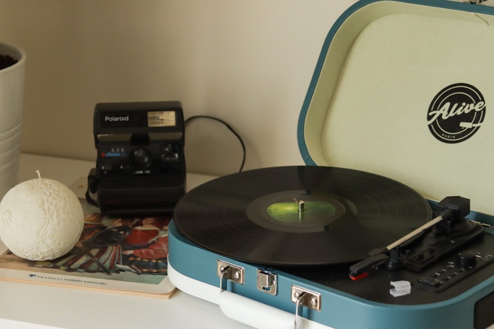 a record player sitting on top of a table next to a cup