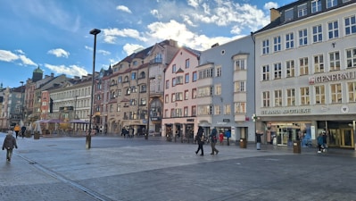 a group of people walking down a street next to tall buildings