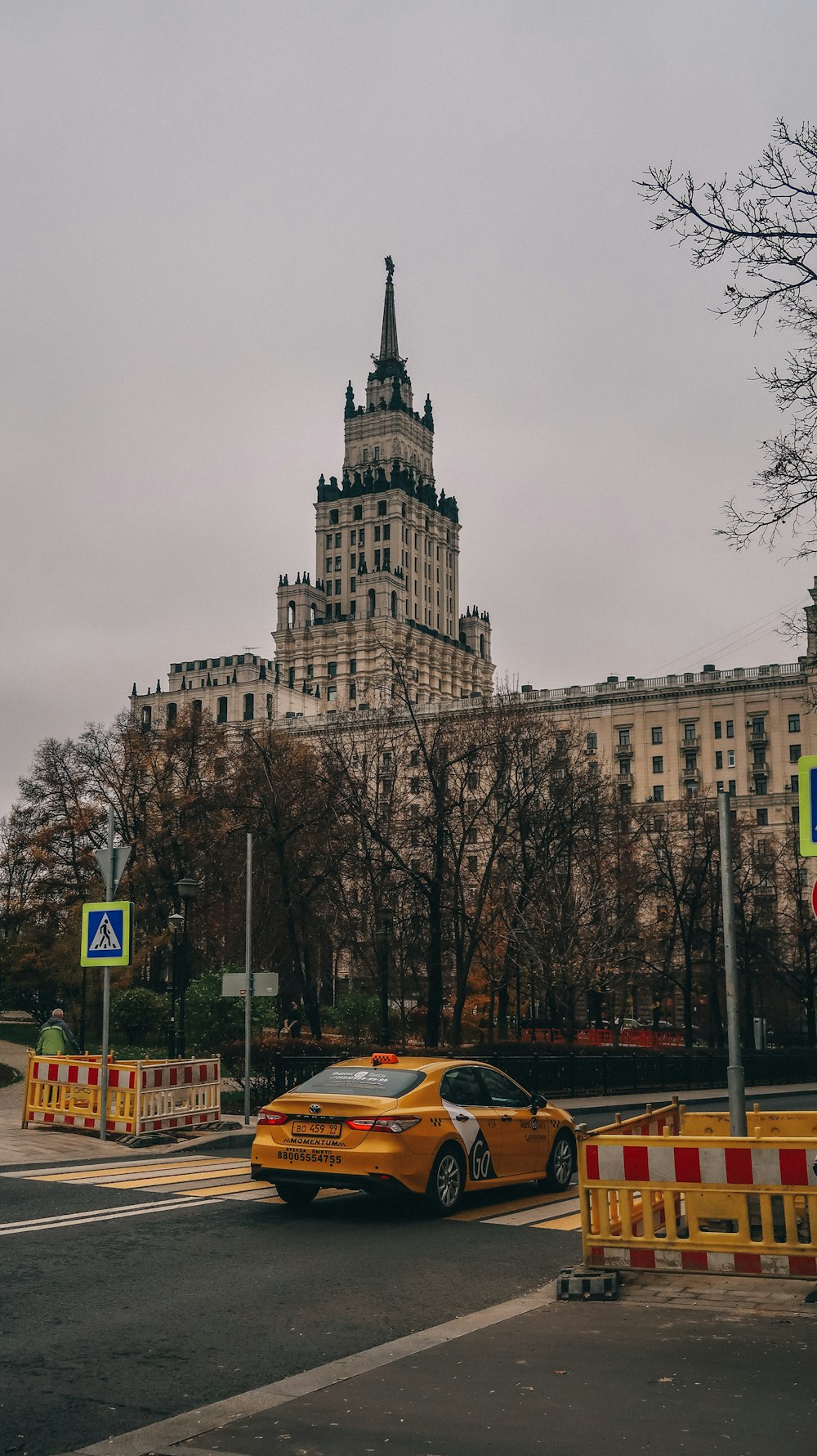 a yellow car driving down a street next to a tall building