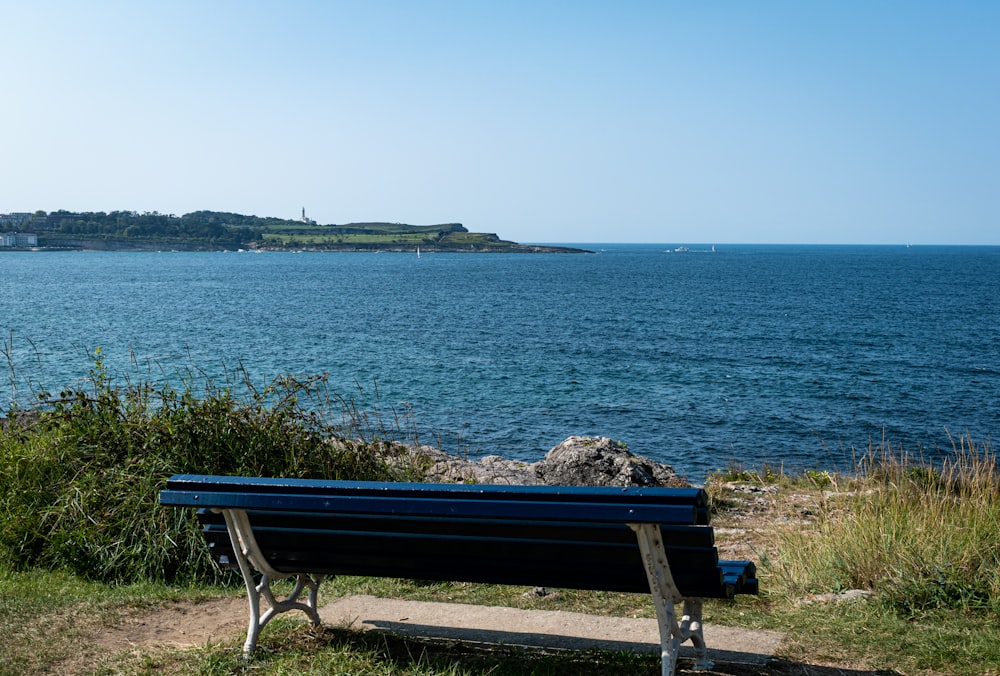 a blue bench sitting on top of a grass covered field