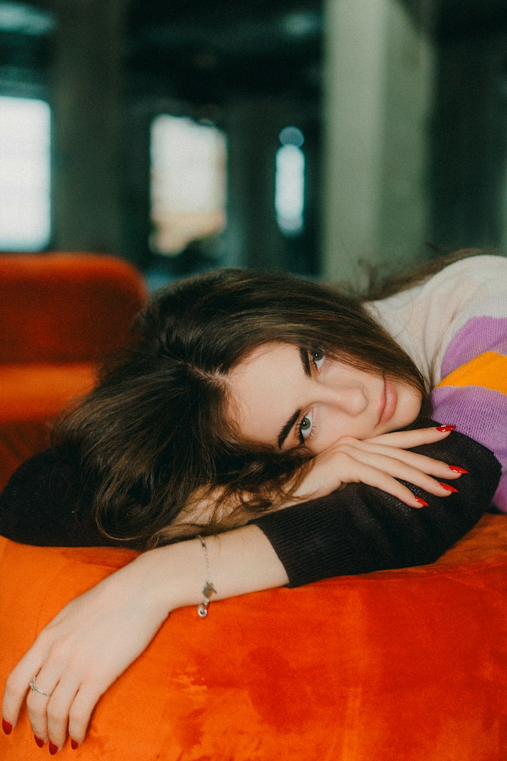 a woman laying on top of an orange couch