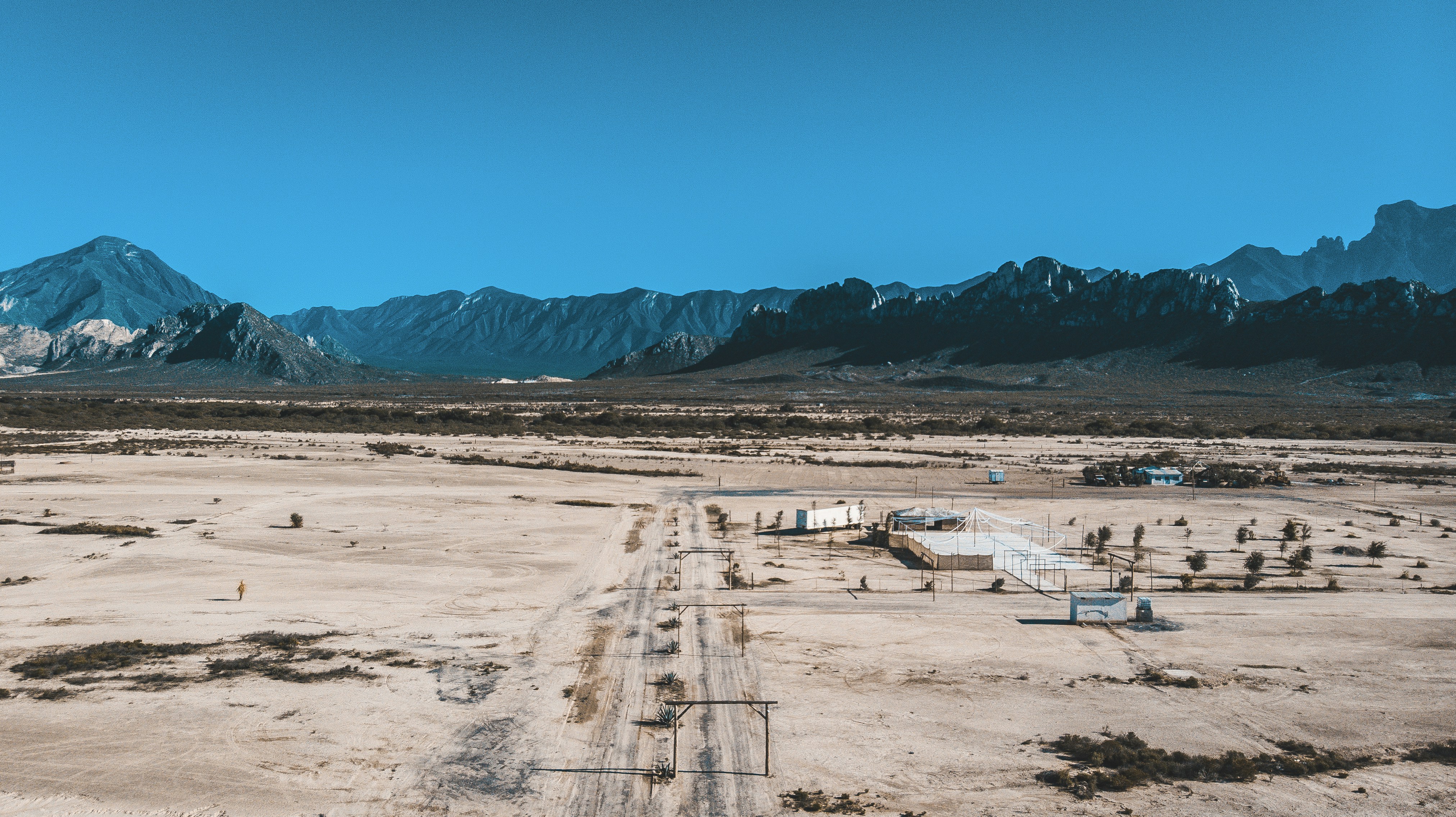 Un camino de tierra en medio de un desierto con montañas al fondo