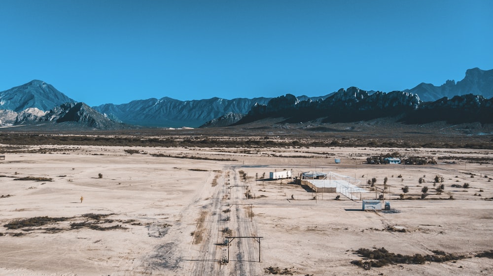 a dirt road in the middle of a desert with mountains in the background