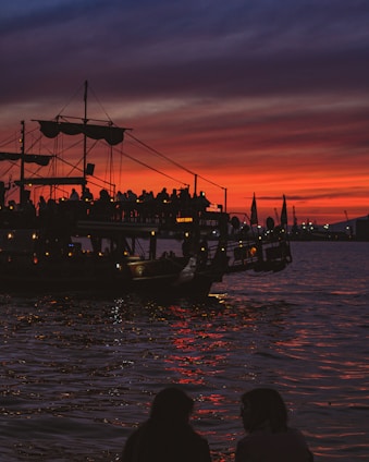 A vibrant cruise ship sailing under a golden sunset with happy travelers on deck.