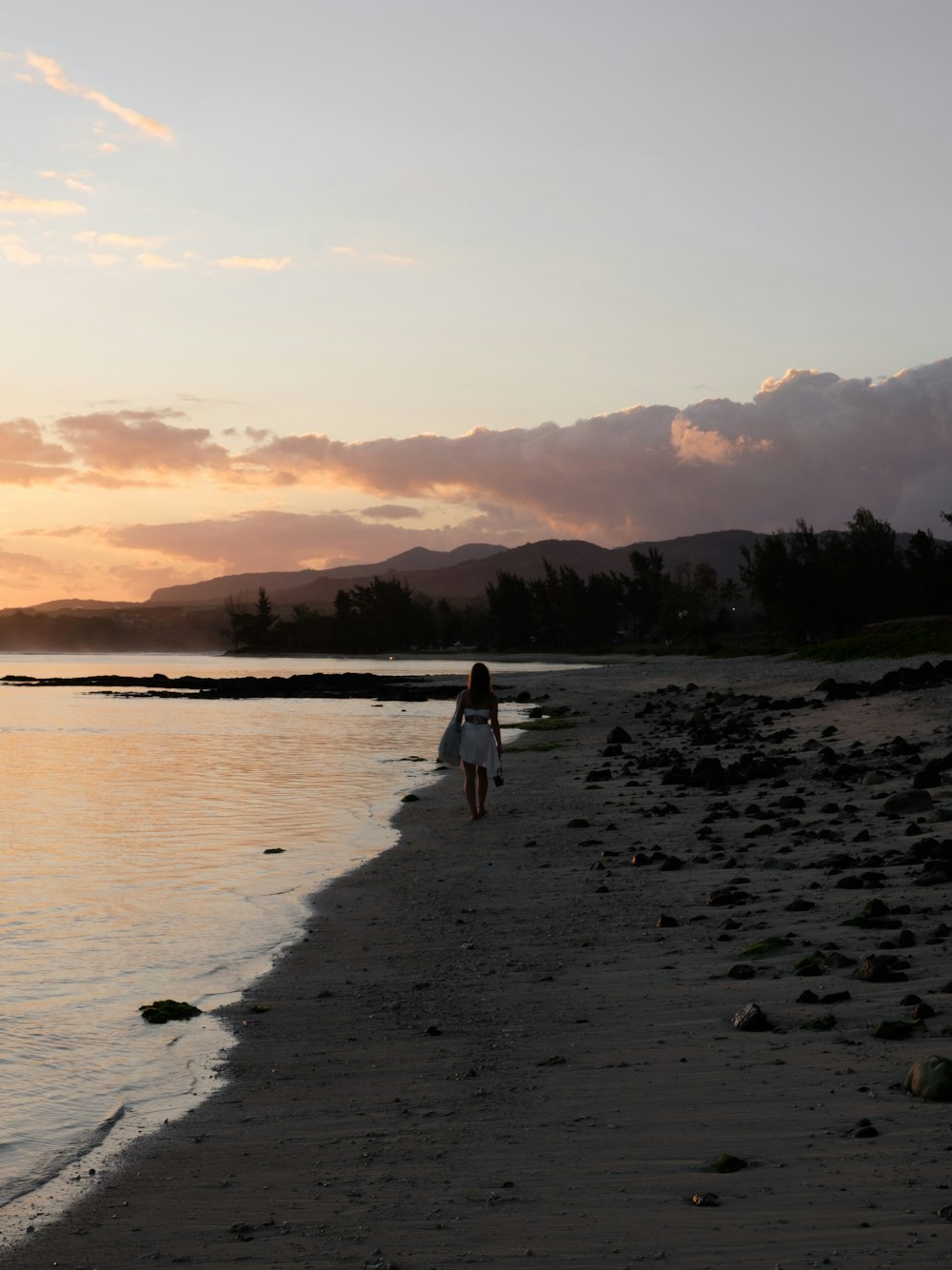 a person walking on a beach at sunset