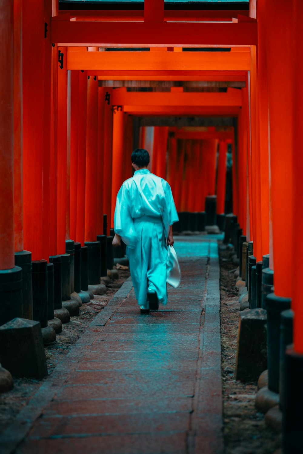 a man in a blue robe walking down a walkway