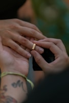 Close-up of a bride’s wrist being tattooed with a fine, elegant design during a wedding ceremony.