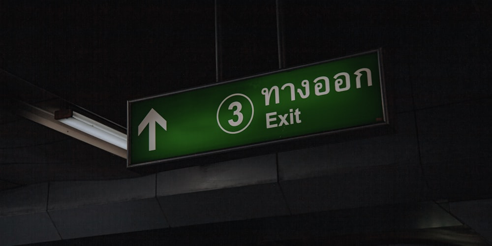 a green exit sign hanging from the side of a building