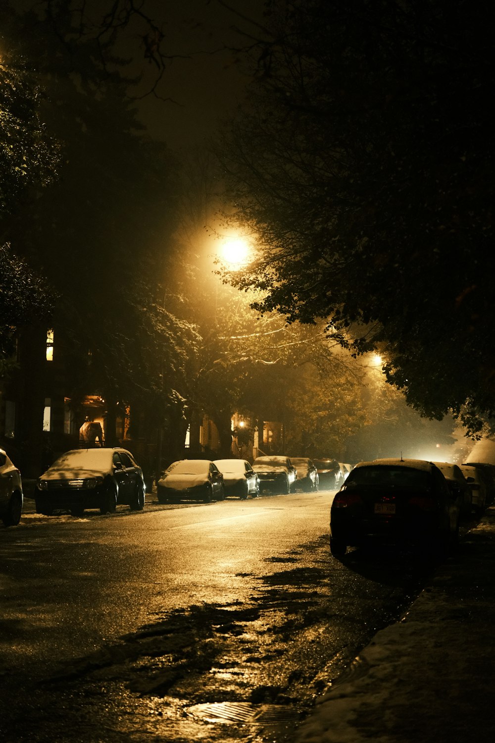 a street at night with cars parked on the side of the road