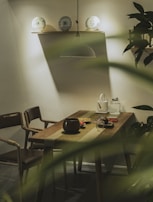 A sleek dining area featuring a light oak table set with neutral-toned ceramics and a delicate linen runner.