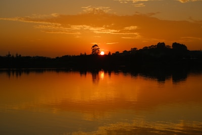 A picturesque sunset over a tranquil lake surrounded by trees.