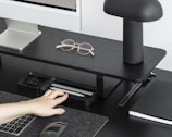 A sleek office desk setup with a minimalist lamp, ergonomic chair, and neatly organized smart office accessories.