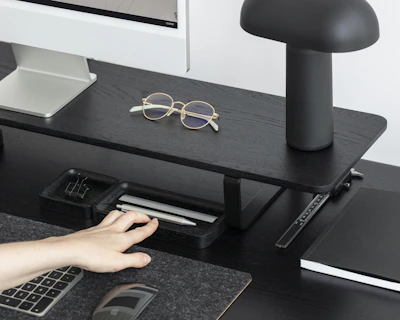 A stylish office desk setup featuring a gold-accented laptop, leather notebook, and elegant black pen holder.