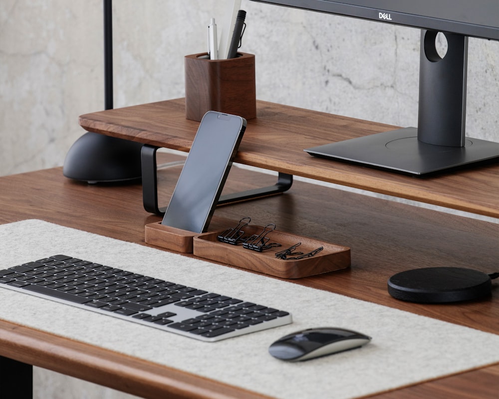 a computer desk with a keyboard, mouse and cell phone