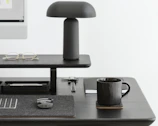 Minimalist desk setup with a sleek black chair and neutral-toned office supplies.