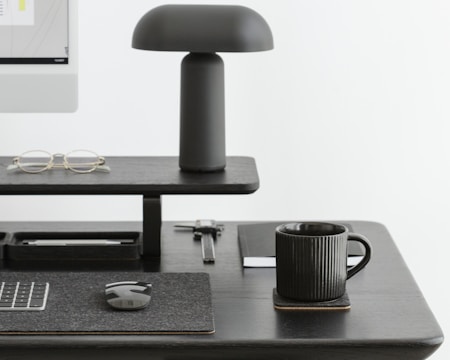 A minimalist desk setup with a sleek lamp, a notebook, and a calming ceramic mug.