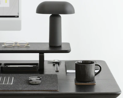 Minimalist desk setup with a sleek black chair and neutral-toned office supplies.