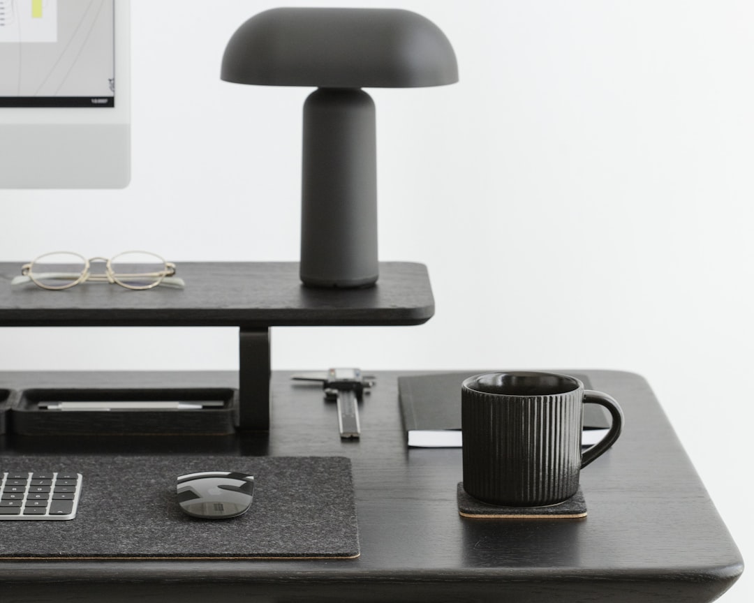 a desk with a computer monitor, keyboard, mouse and glasses,