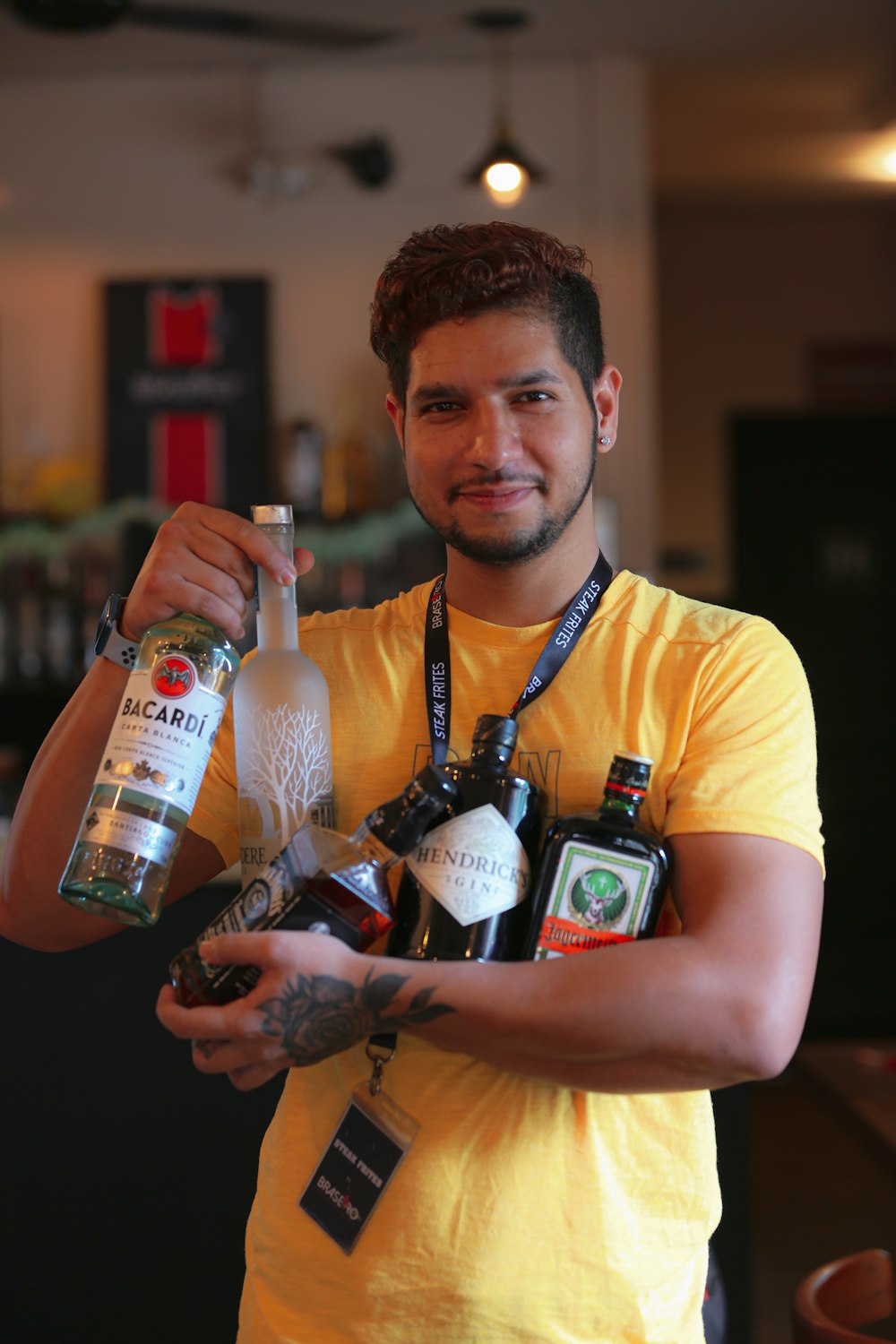 a man in a yellow shirt holding a bottle of alcohol