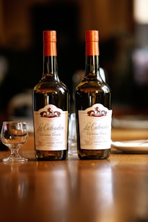 two bottles of wine sitting on top of a wooden table