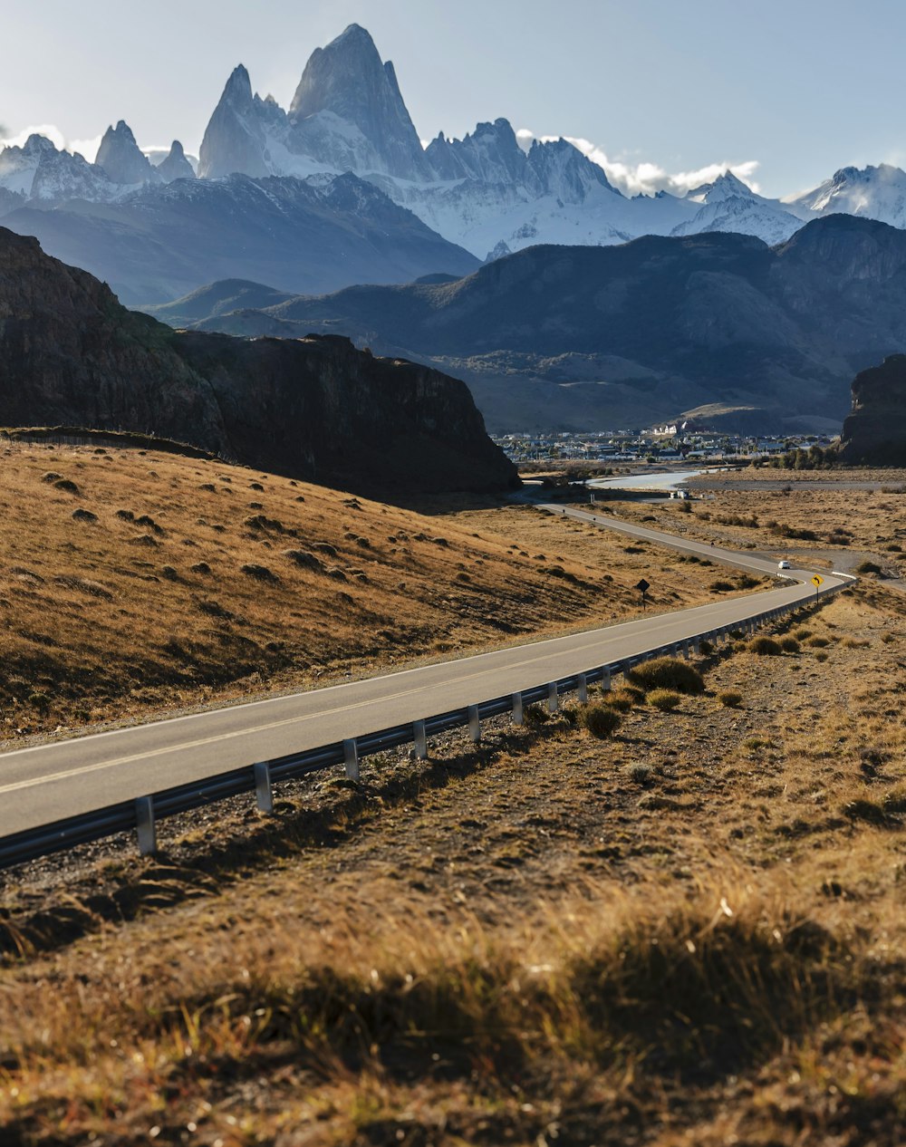 a road in the middle of a field with mountains in the background