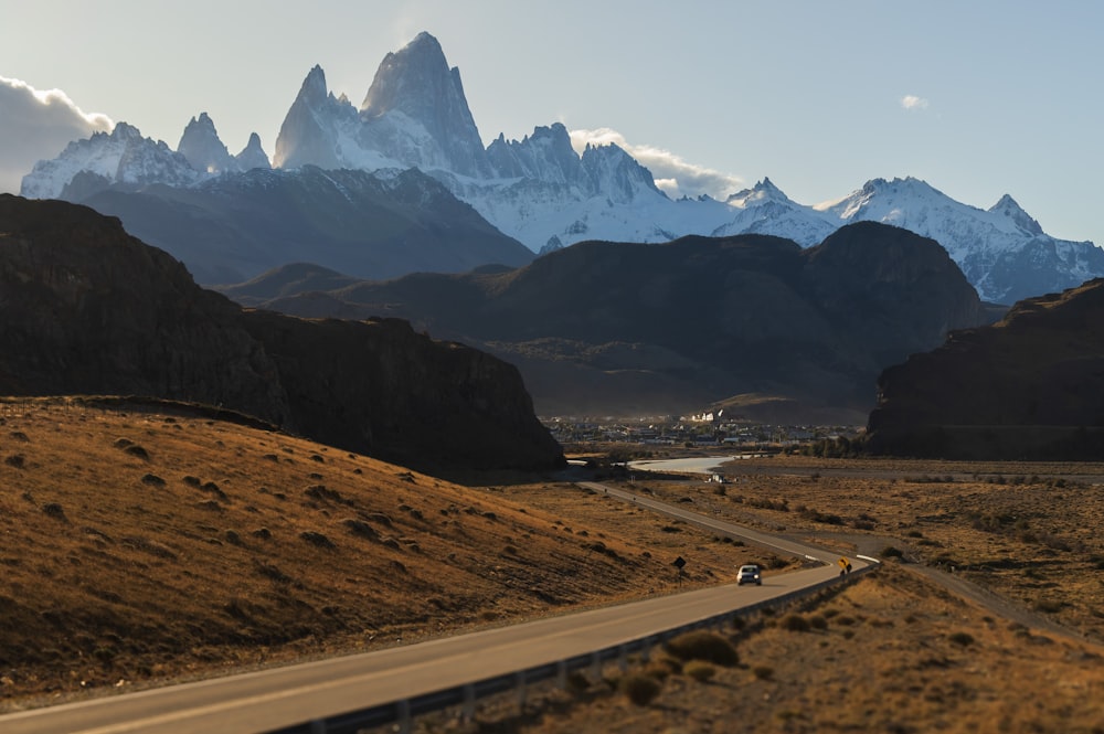 a car driving down a road with mountains in the background