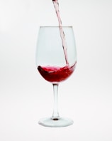 Close-up of a wine glass being filled with red wine, highlighting the rich color.