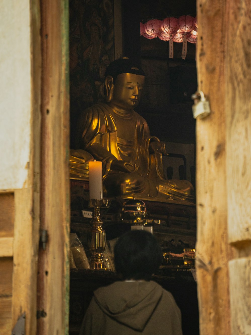a person standing in front of a golden buddha statue