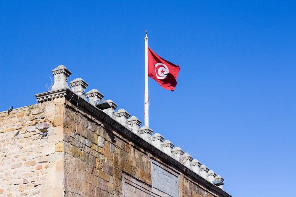 a red flag flying on top of a stone building