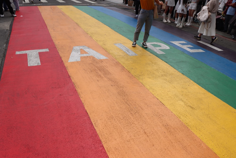 a rainbow painted street with people walking on it
