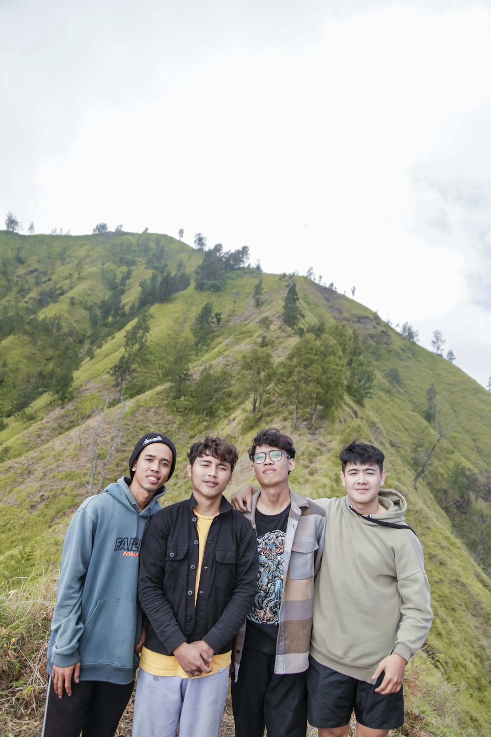 a group of young men standing on top of a lush green hillside