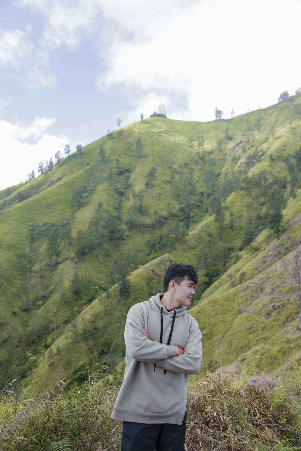 a man standing in front of a lush green hillside