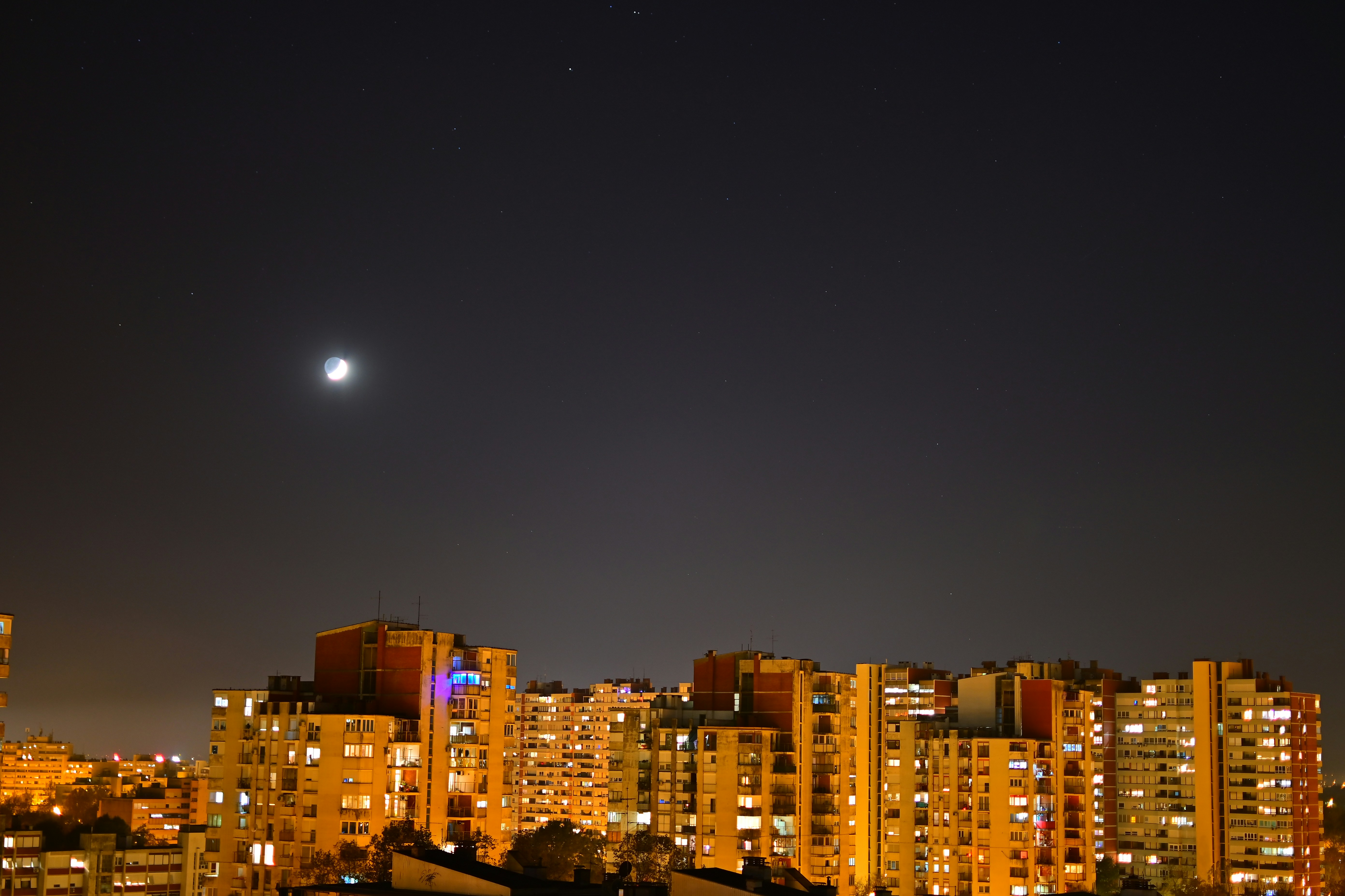 A city at night with the moon in the sky