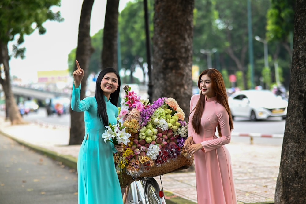 two women standing next to each other holding a basket of flowers