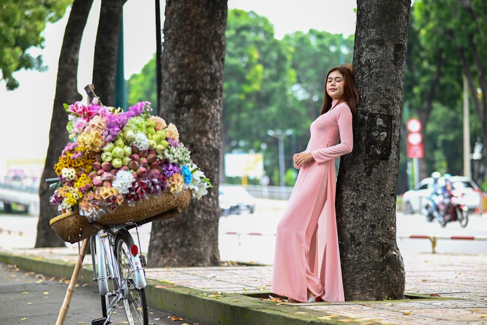a woman standing next to a bike with a basket of flowers on it