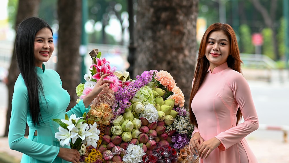 two beautiful women standing next to each other holding flowers