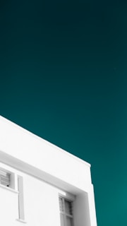 A minimalist architectural photo featuring clean lines and shadows on a sleek modern building facade against a deep twilight sky.