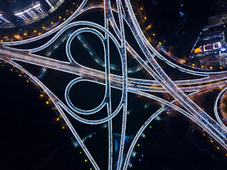 A dynamic aerial shot of a sprawling highway interchange illuminated at dusk, symbolizing intricate, high-speed connectivity.