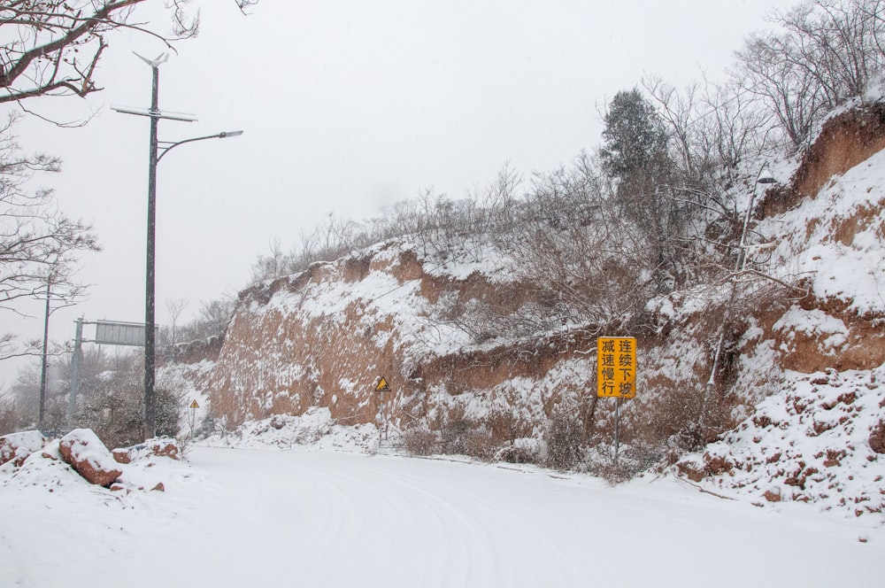 a snow covered road with a yellow sign on it